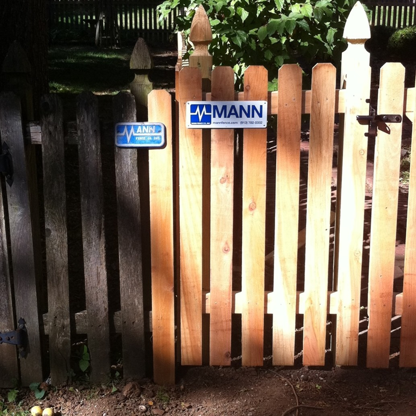 A newly installed wooden picket fence section by Mann Fence Co., Inc. in Olathe, KS.
