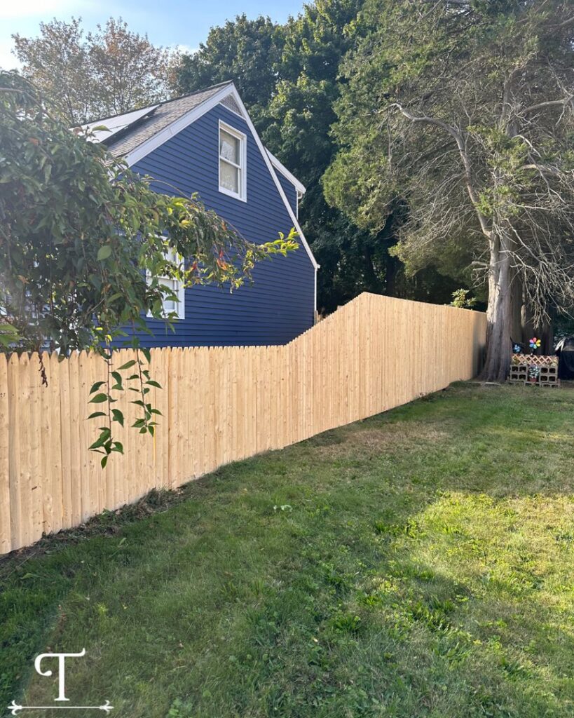 A newly installed wooden picket fence running along a residential property by Teto's Fence Installation in Bridgeport, CT.