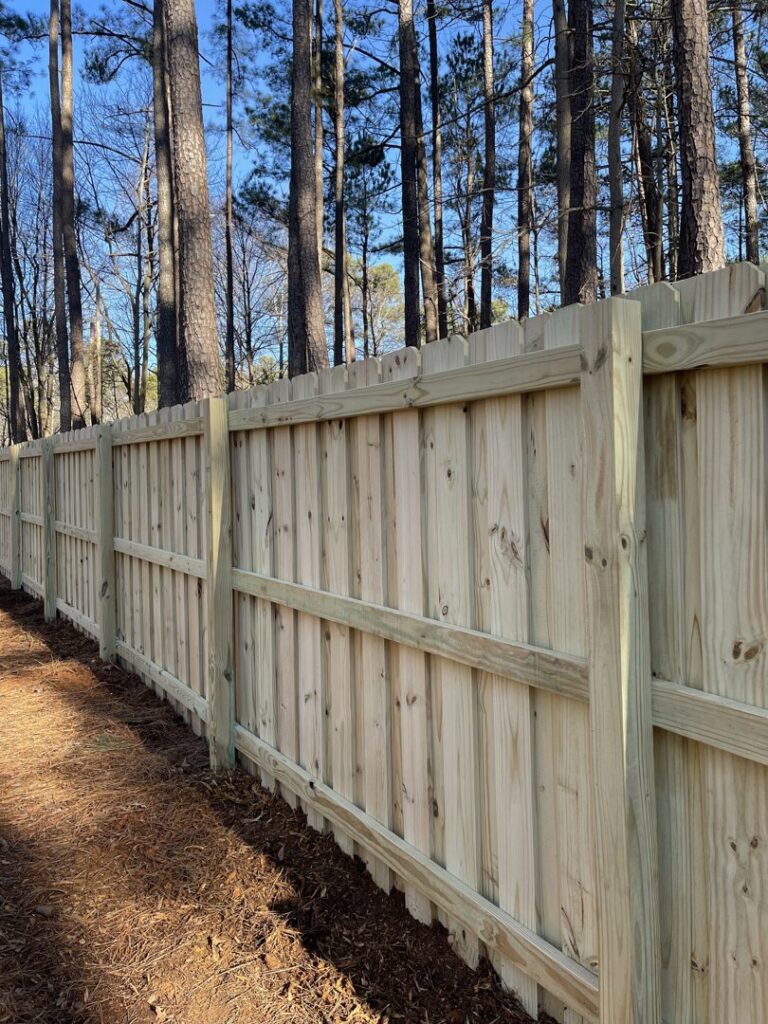A newly installed wooden privacy fence running along a treeline by Align Fence Builders in Durham, NC.