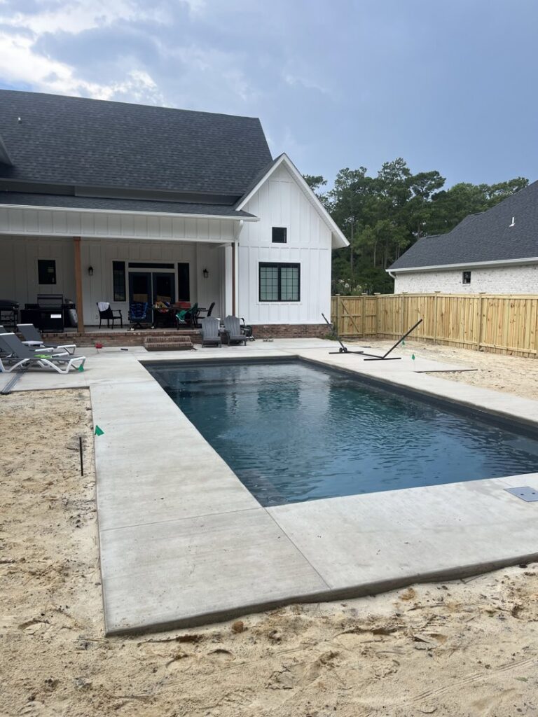 A newly installed wooden privacy fence enclosing a backyard with a swimming pool by Heavenly Gates Construction LLC in Miami, FL