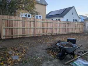A newly installed wooden privacy fence in a residential backyard by Fence Pros Direct in Saunderstown, RI.