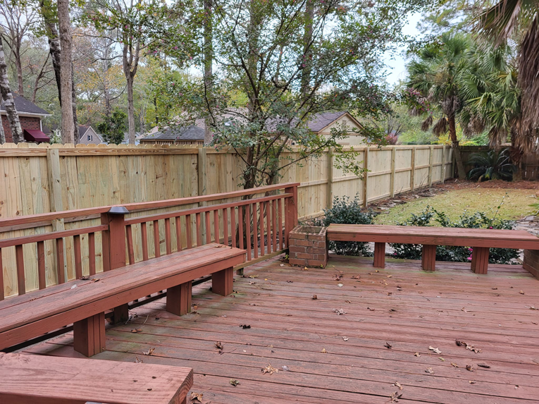 A newly installed wooden privacy fence in a backyard with a deck by Lundquist Home Improvements in Mount Pleasant, SC.