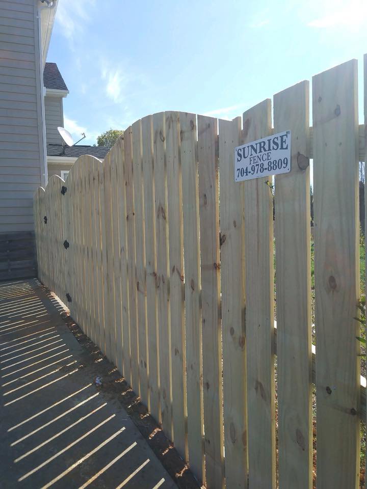 A new wooden privacy fence with a decorative curved top installed by Sunrise Fences in Monroe, NC.