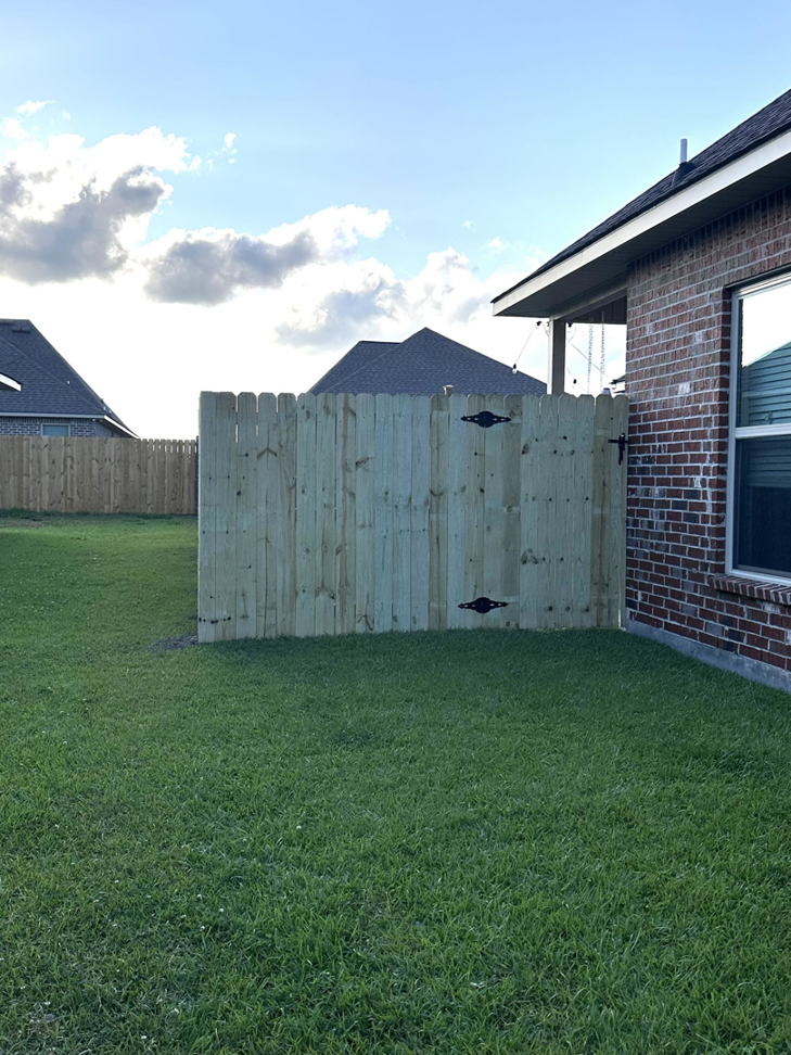 A newly installed wooden privacy fence gate with decorative hinges by Gator Fence Co. in Miami, FL