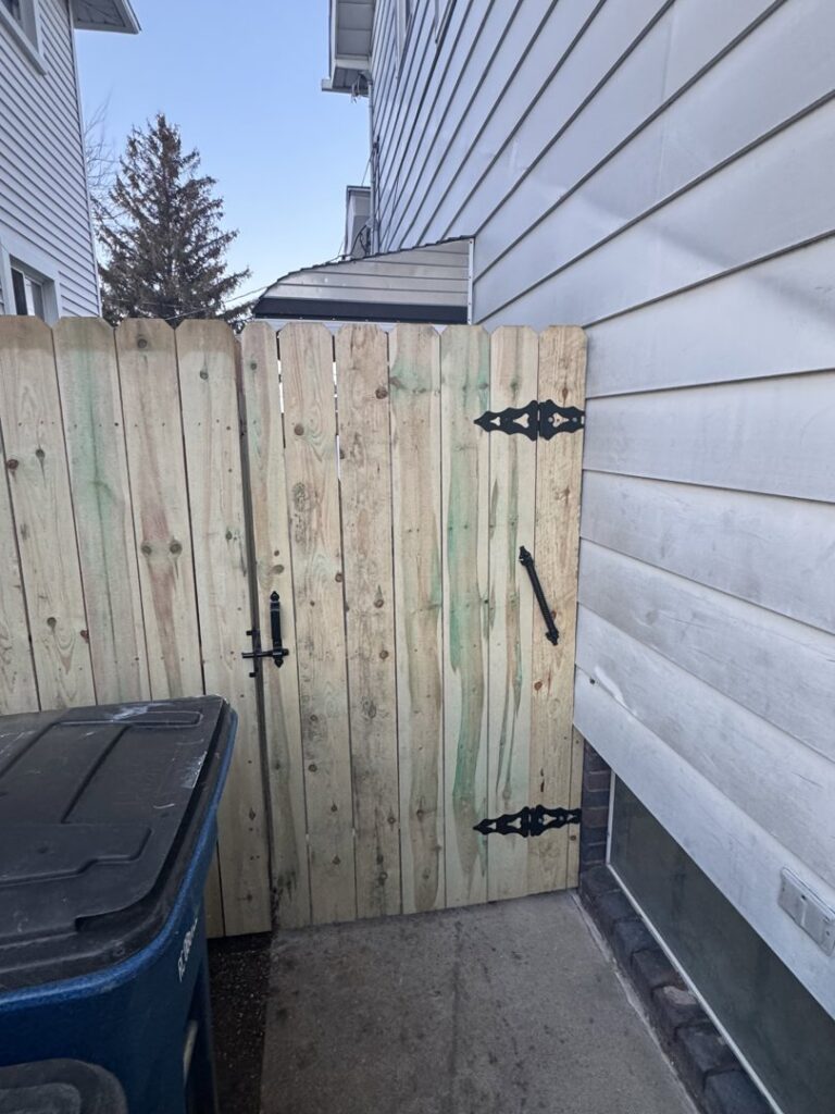 A newly installed wooden privacy fence gate with decorative hardware by Premier Fence LLC in Canton, MA.