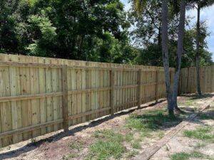 A newly installed wooden privacy fence along a property line by Golden Eagle Fencing in Tampa, FL