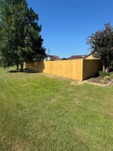 A newly installed wooden privacy fence in a residential yard by Smithfield Fence in Crowder, MS.