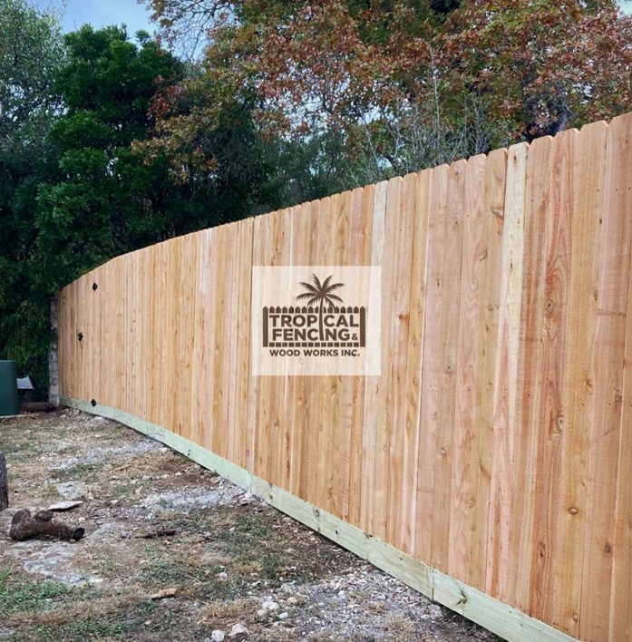 A newly installed wooden privacy fence with a green baseboard by Tropical Fencing And Wood Works in Page, TX.