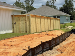 A newly installed wooden privacy fence next to a residential home by Integrity Construction and Fencing, LLC in Clanton, AL.