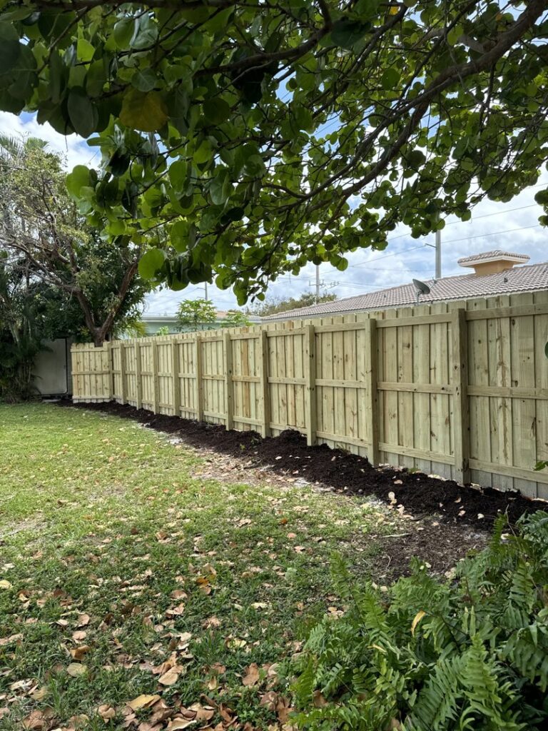 A newly installed wooden privacy fence with fresh landscaping by Ace Fence Company in Fort Lauderdale, FL.
