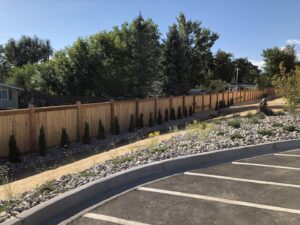 A long, newly installed wooden privacy fence bordering a parking lot, completed by First Rate Fence & Supply in Denver, CO.