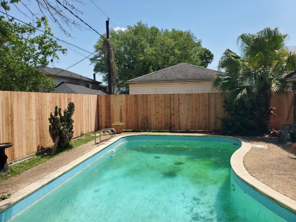 A newly installed wooden privacy fence surrounding a swimming pool by 5-Alarm Fence Company in New Orleans, LA.