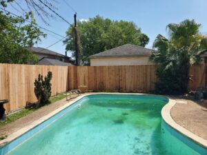A newly installed wooden privacy fence surrounding a swimming pool by 5-Alarm Fence Company in New Orleans, LA.