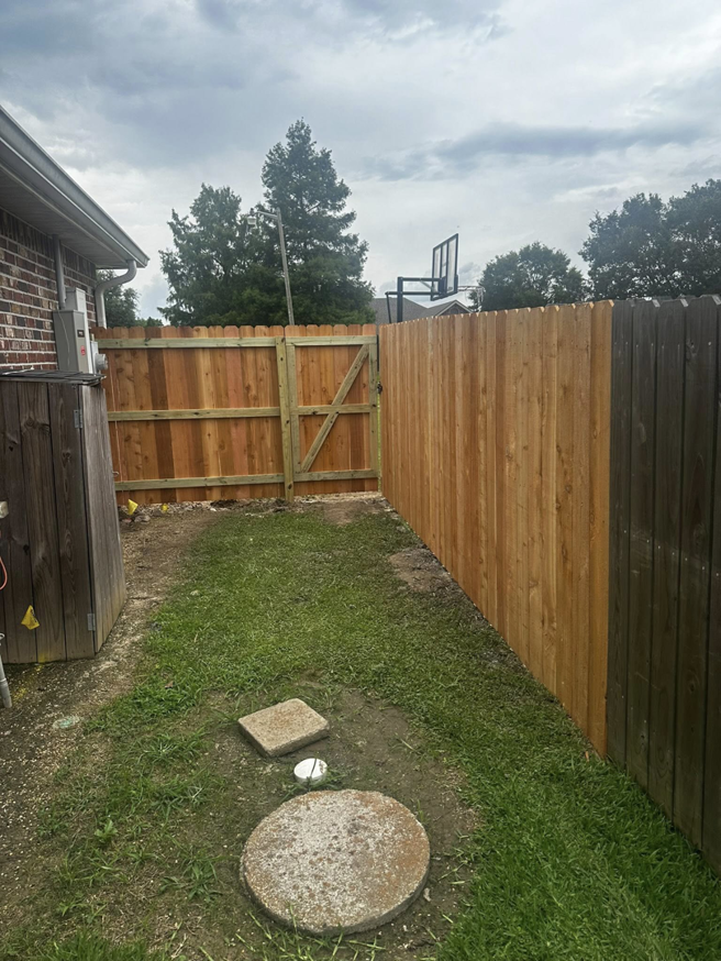A newly installed wooden privacy fence with a gate next to an existing fence by J&L Fence in Zolfo Springs, FL.