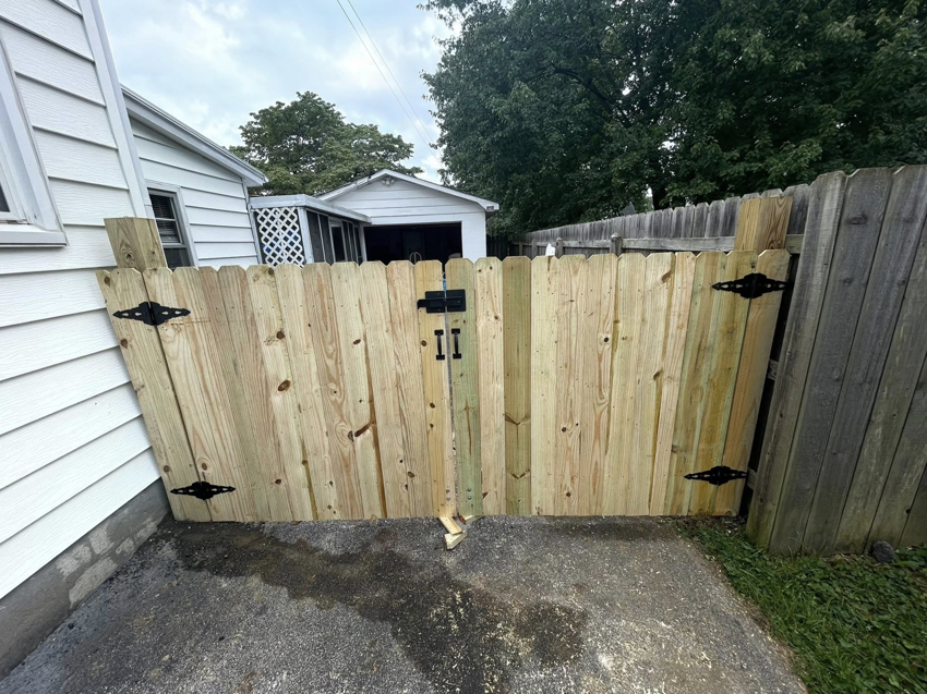 A newly installed wooden privacy gate with black hardware next to a house by JV Fences in Lexington, KY.