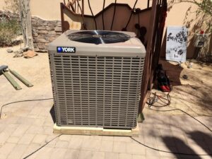 A newly installed York brand outdoor AC condenser unit on a wooden pad by Hellerud Air in Peoria, AZ.