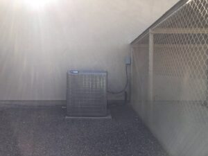 A newly installed York brand outdoor AC condenser unit next to a building wall by Hellerud Air in Peoria, AZ.