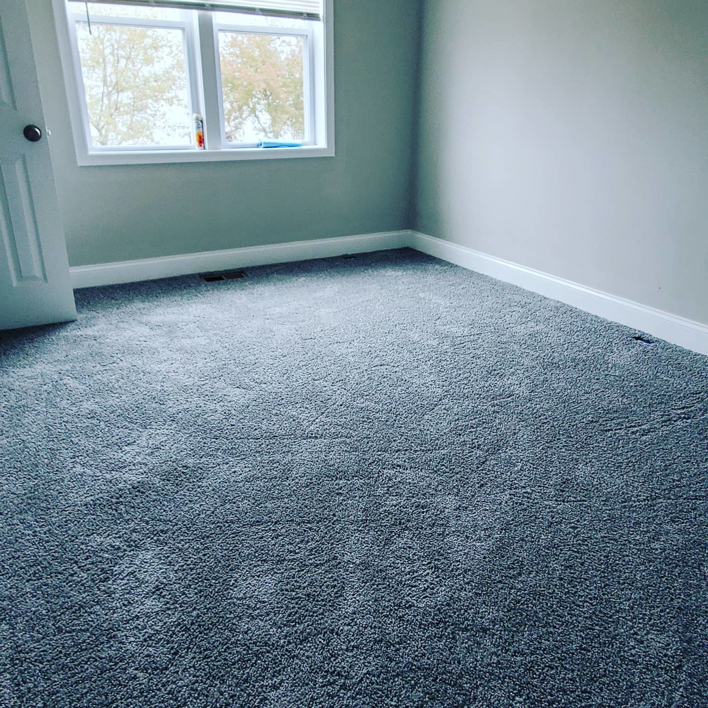 An empty residential room featuring newly installed grey carpet by Yankees Carpet Inc in Baltimore, MD