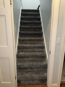 A newly carpeted staircase with gray carpet installed by Carpet Warehouse Lorain LLC in Lorain, OH.