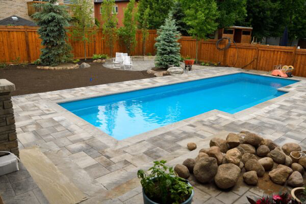 A newly installed backyard swimming pool with elegant paver decking by Polar Pool and Spa in Vancouver, WA.