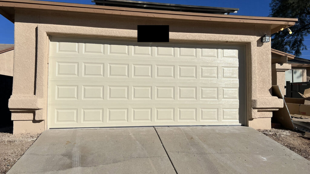 A newly installed beige panel garage door on a residential home by Tucson Garage Door Doc in Tucson, AZ.