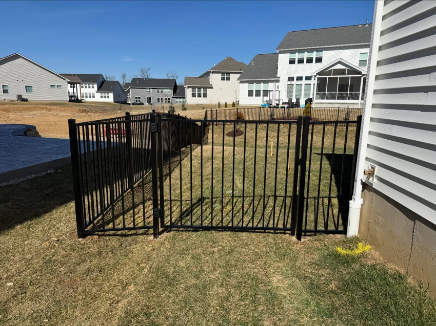 A newly installed black aluminum fence with a gate in a residential backyard by BK FenceWorks in Wentzville, MO.