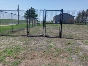 A newly installed black chain-link fence with double gates by Stallworth Home Improvement in Des Moines, IA.