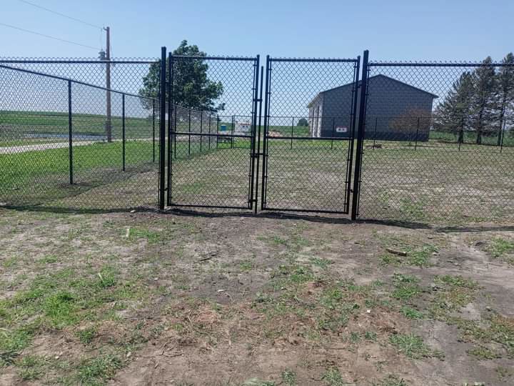 A newly installed black chain-link fence with double gates by Stallworth Home Improvement in Des Moines, IA.