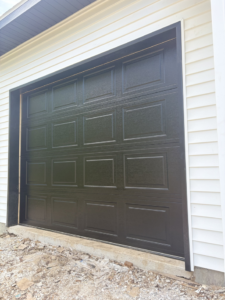 A newly installed black garage door on a residential home by Ozarks Overhead Door & More in Springfield, MO.