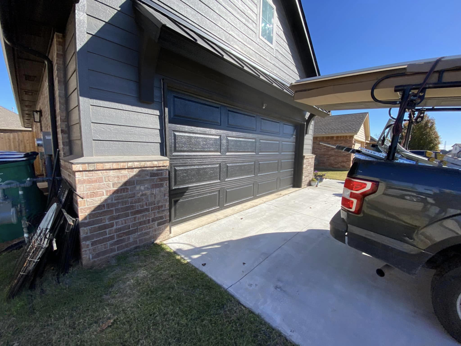 A newly installed or well-maintained black garage door on a modern home by Unhinged Garage Doors LLC in Oklahoma City, OK.