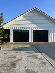 Newly installed black garage doors on a white house by Specialty Garage Door in Bossier City, LA