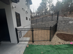 A newly installed black metal fence with a gate next to a house by Denfence Team in Colorado Springs, CO