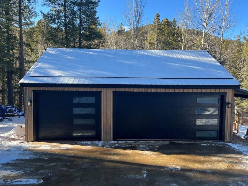 A detached garage featuring two newly installed black modern garage doors with horizontal windows by PNG Garage Doors llc in Lakewood, CO.