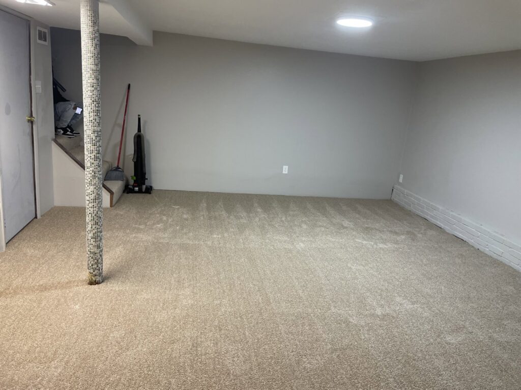 A newly installed light beige carpet in a finished basement room by JJS Flooring & Decorating Co Inc in Saint Louis, MO.