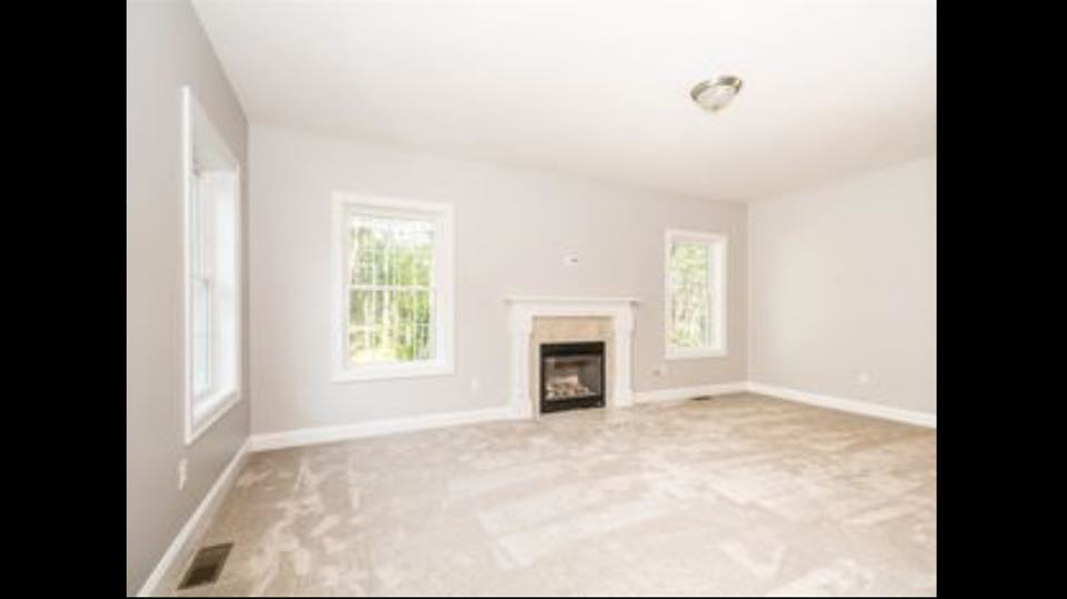 A bright living room featuring newly installed light-colored carpet by The Vaira Companies, LLC in Londonderry, NH.