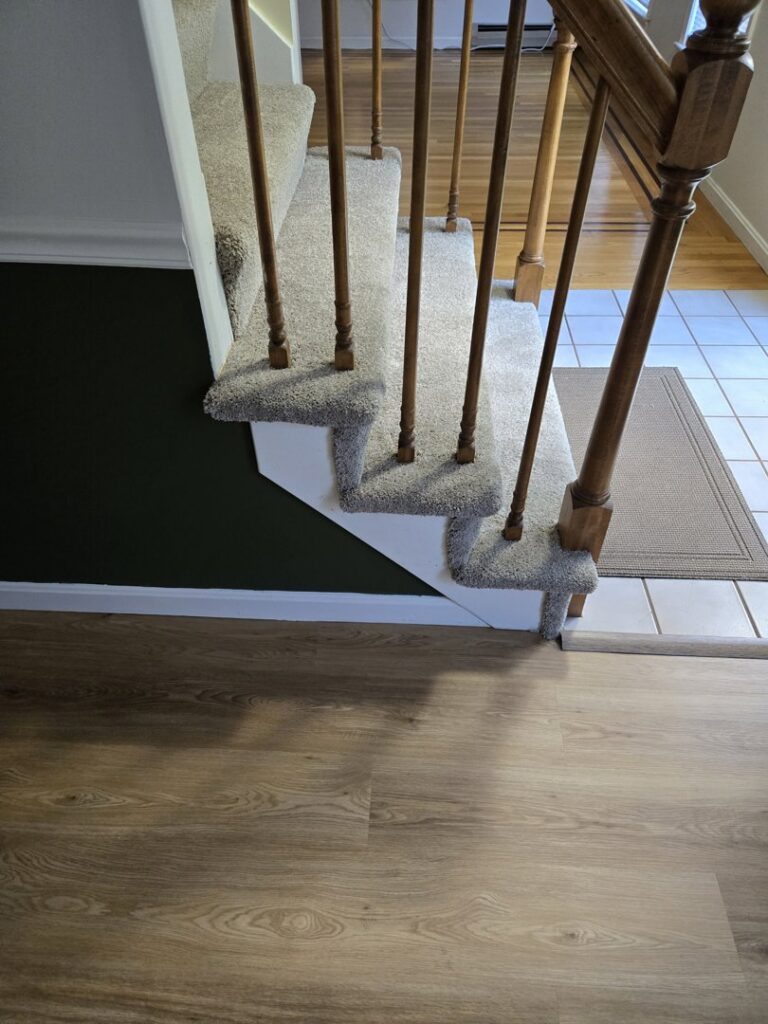 Newly installed carpet on a staircase by Essex Companies LLC in Salem, NH, transitioning to wood flooring.