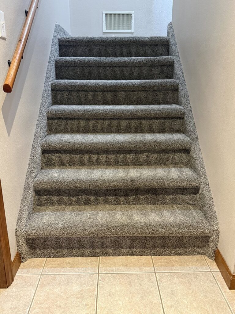 A newly installed grey carpet on a staircase, showcasing carpet contractor work by North Colorado Kwik Dry Total Cleaning in Johnstown, CO.
