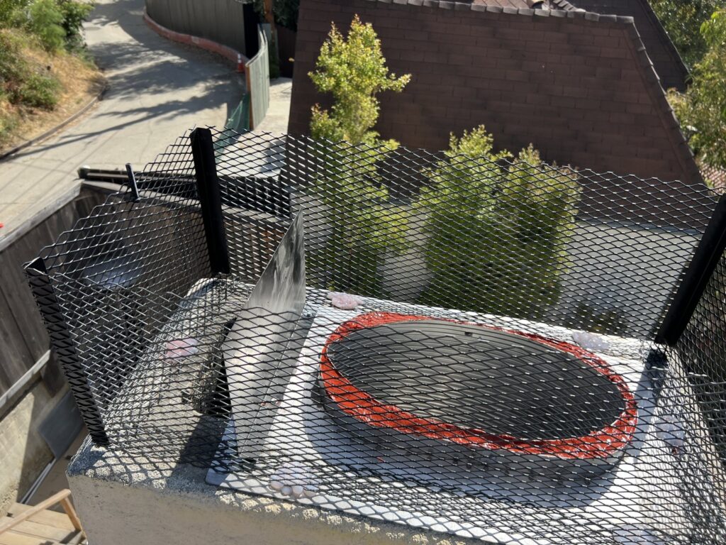 A newly installed metal mesh chimney cap on a rooftop, a service provided by Fireplace Freddie in Shadow Hills, CA.