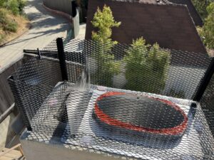 A newly installed metal mesh chimney cap on a rooftop, a service provided by Fireplace Freddie in Shadow Hills, CA.