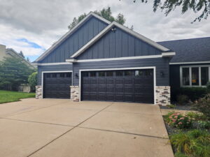 Newly installed dark garage doors with windows on a house by LabraDoor Overhead Services in Eau Claire, WI.