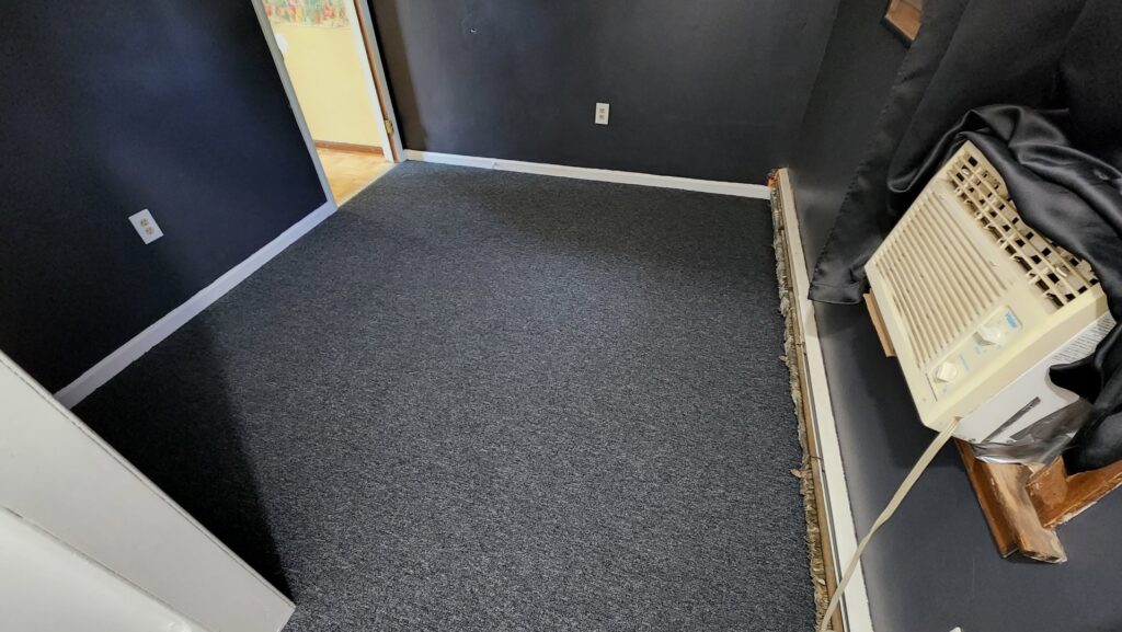 A newly installed dark grey carpet in a room, showcasing the quality work by Carpet Maven Flooring in Woodbridge, NJ.