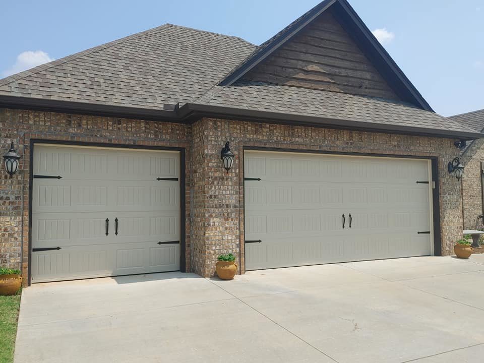Two newly installed garage doors with decorative hardware on a brick home by Total Door Solutions in Yukon, OK