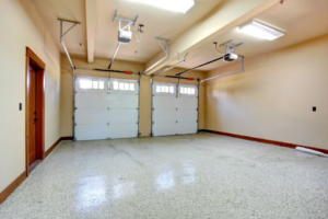 Interior view of a garage with two newly installed white garage doors and openers by Integrity Garage Door Repair in Clearwater, FL.