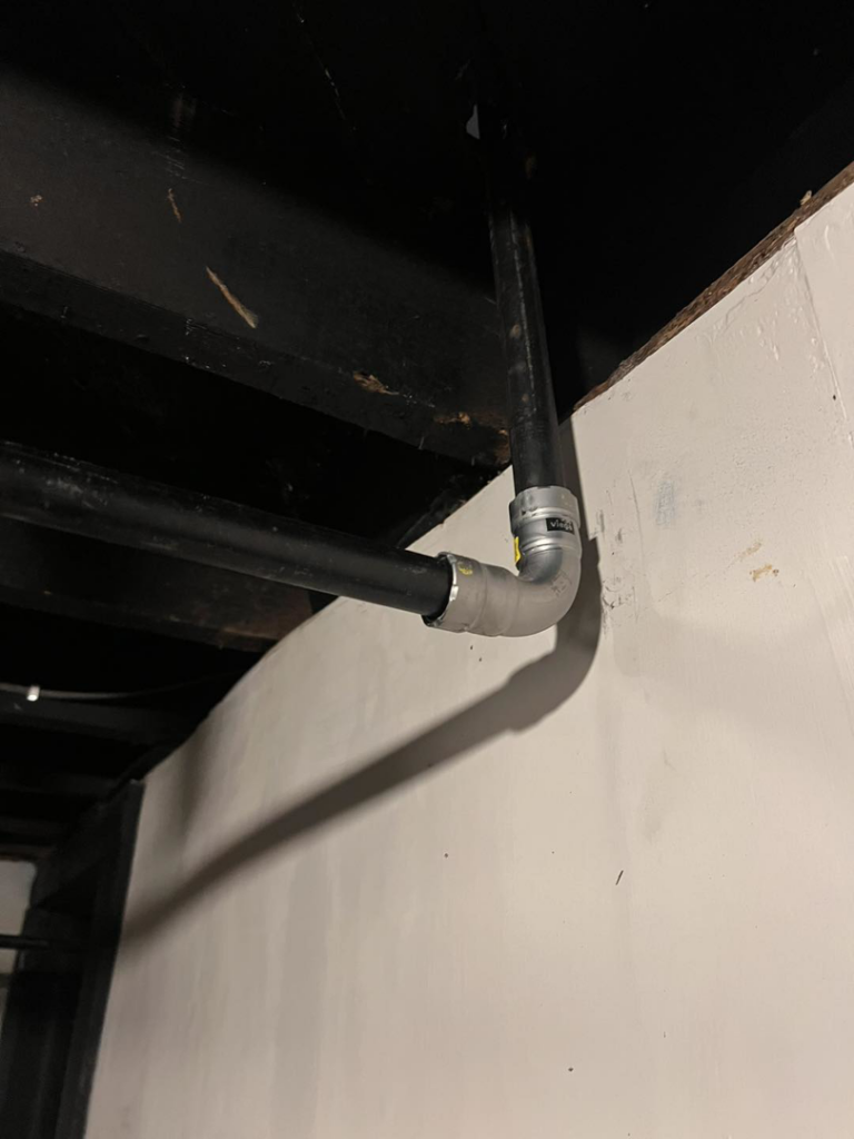 Newly installed black gas piping running along a basement ceiling, showcasing work by Basurto's Heating & Cooling in Milwaukee, WI.