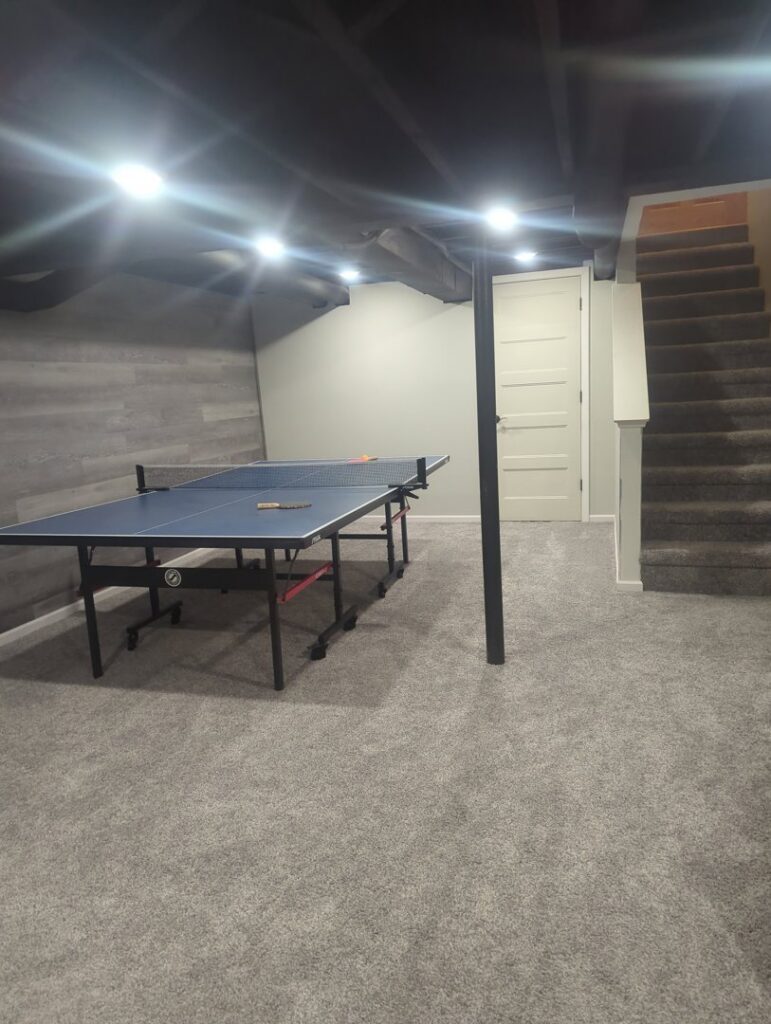 Newly installed gray carpet in a finished basement with a ping-pong table by Nelson Floor Covering in Westland, MI