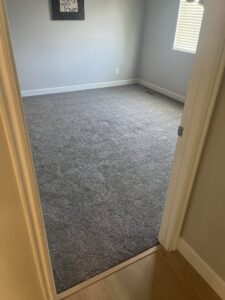 A newly installed gray carpet in a bedroom, showcasing a professional carpet contractor job by TL Floor & Design - Layton in Layton, UT.