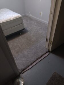 A newly installed gray carpet in a bedroom with a bed by Carpet Mart of Idaho Falls in Idaho Falls, ID.