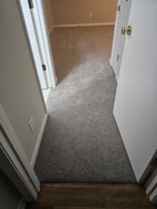 Newly installed gray carpet in a residential hallway and room by Wholesale Carpet of Sumter in Sumter, SC.