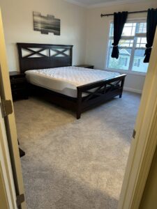 A bedroom featuring newly installed light grey carpet by Atlas Flooring & Design in Raleigh, NC.