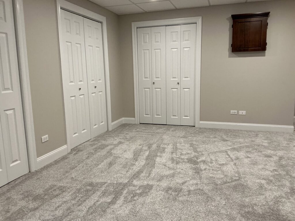 A room featuring newly installed light grey carpet by At Home Flooring in Naperville, IL.